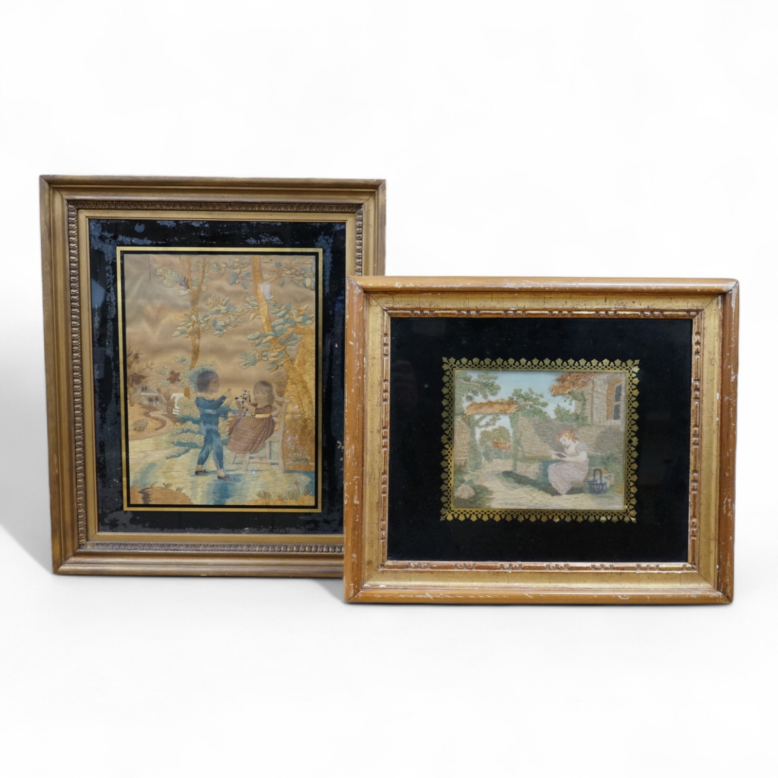 Two early 19th century silk worked embroideries one of two children with a cat, the other of a seated lady reading. Both within Verre Eglomise glass and framed. Largest 32cm x 24cm.